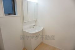 同仕様写真。三面鏡つき洗面台。収納も一体型になっているので、ドライヤーやヘアアイロンの置き場に困りませんね。